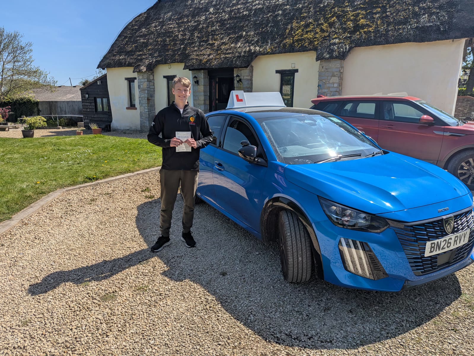 A successful learner beside Matty's blue Peugeot 208 GT tuition car