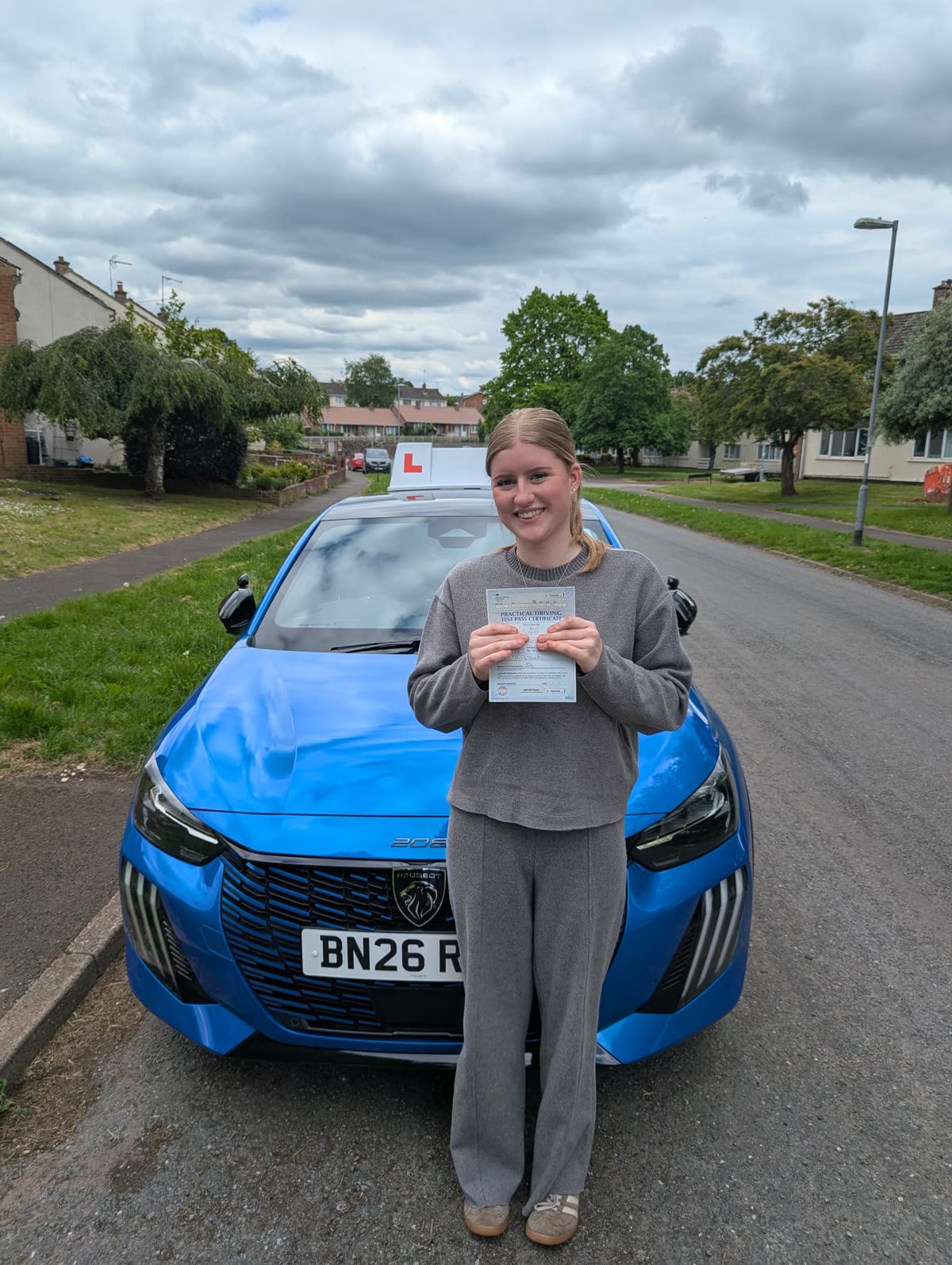 A learner celebrates passing their driving test in front of the tuition car