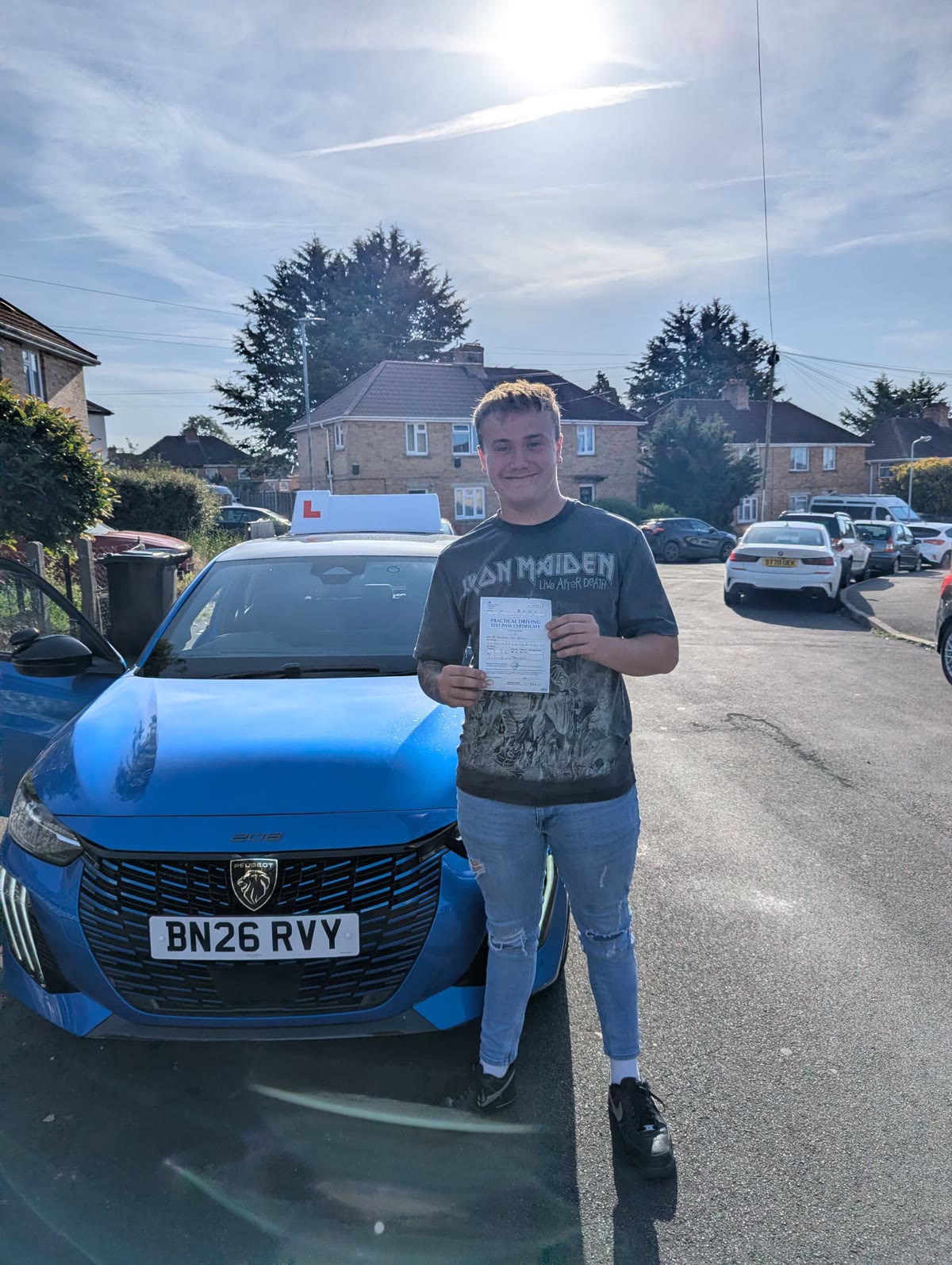 A learner holds their test pass certificate beside the tuition car